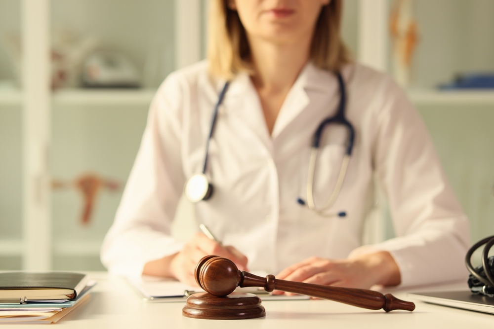 A female doctor sitting behind a gavel to represent medical malpractice