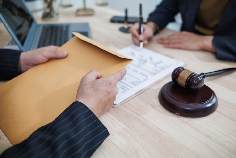 Client shares documents during a mesothelioma lawyers consultation with legal paperwork on the desk.